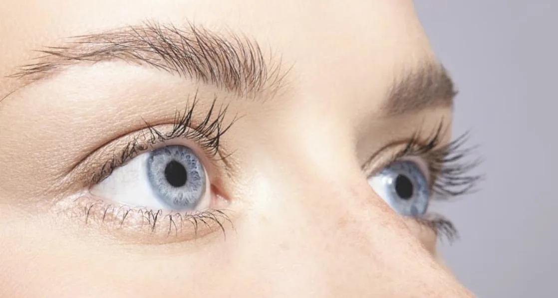 Close-up of a woman's eyes looking upward, with the upper eyelid crease visible